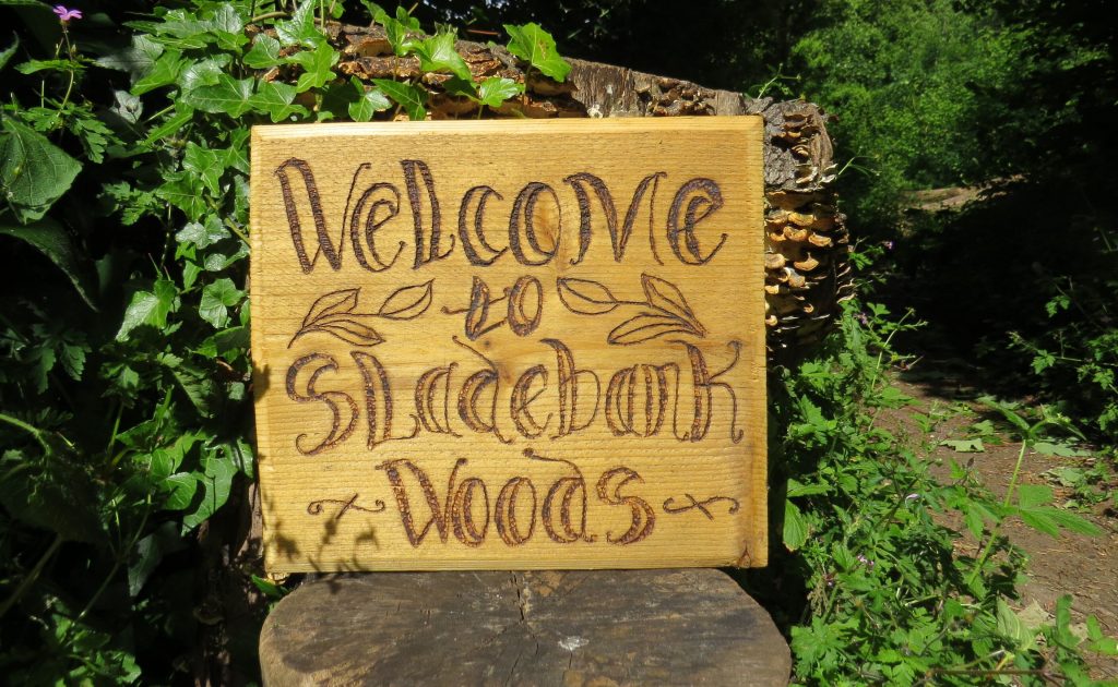 Wooden sign with text saying Welcome to Sladebank Woods